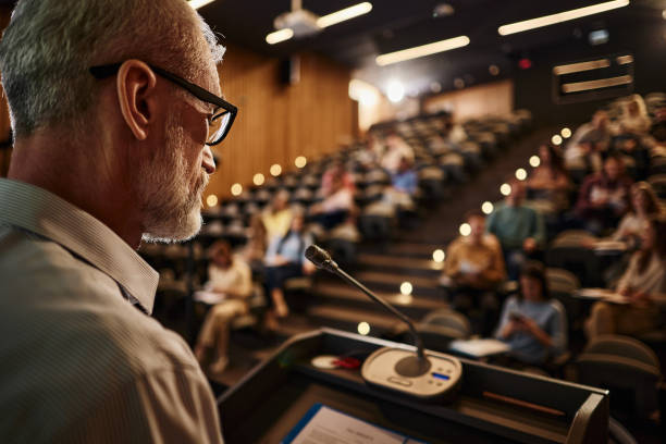 istock Mature professor giving a speech on a class at lecture hall. 2122157776