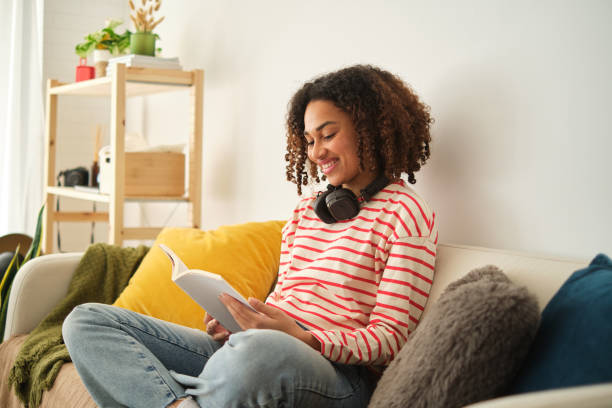 istock Young african woman reading sitting on the sofa 2122205384