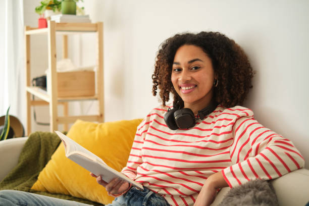 istock Woman smiling at camera while reading relaxed on the sofa 2122208031