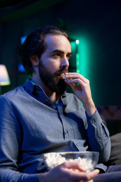 istock Mesmerized eating popcorn and being captivated by movie scenes 2122226325