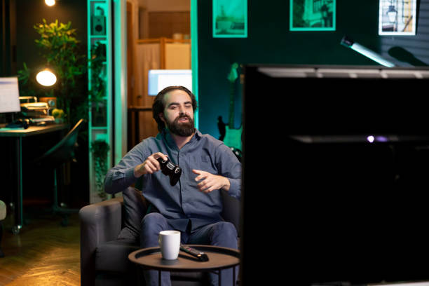 istock Happy man playing shooter videogame in neon illuminated home 2122236588