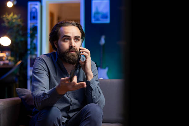 istock Supporter at home analyzing match on TV with mate during phone call 2122248459