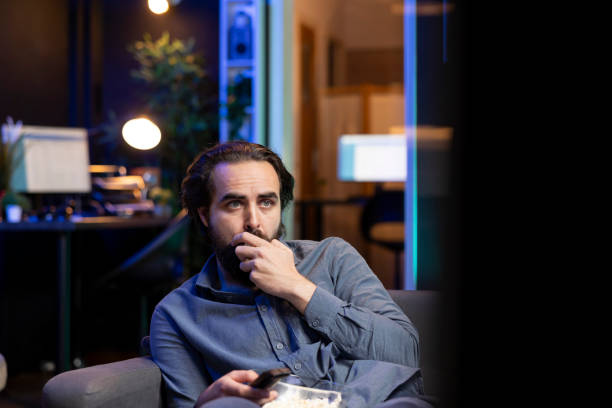 istock Sad man on couch eating popcorn from stress while watching heartbreaking drama 2122255766