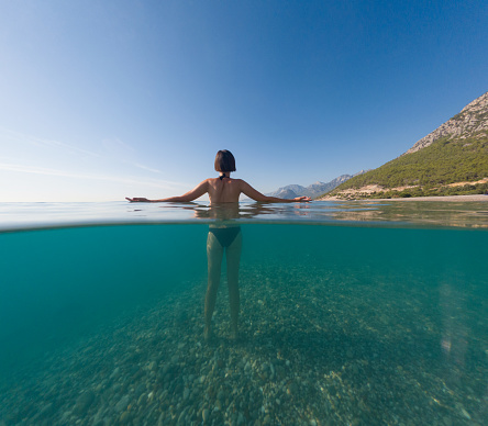 Woman on tropical vacation paradise on sea. Summer sea joy in Turkish seacoast, beaches along Lycian Way, Turkish Riviera. Asian female underwater and turquoise ocean around.