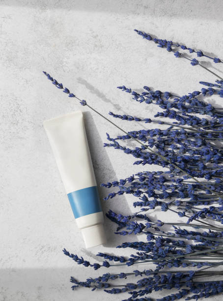 istock Top view of whte blank tube and lavender flowers on bright surface.Empty space.Vertical image 2122281839