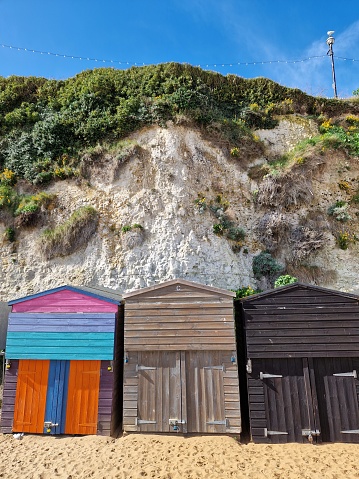 Bright, colorful beach huts on sandy beach on the Kentish coast, Kent, UK