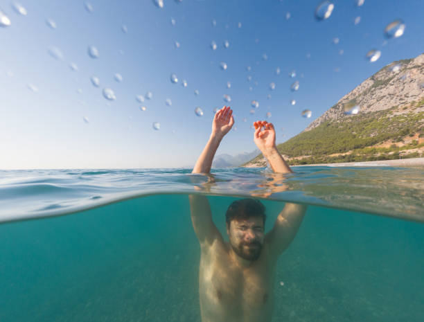 Sea summer landscape. young man sinking into the sea, under and above waterline,
