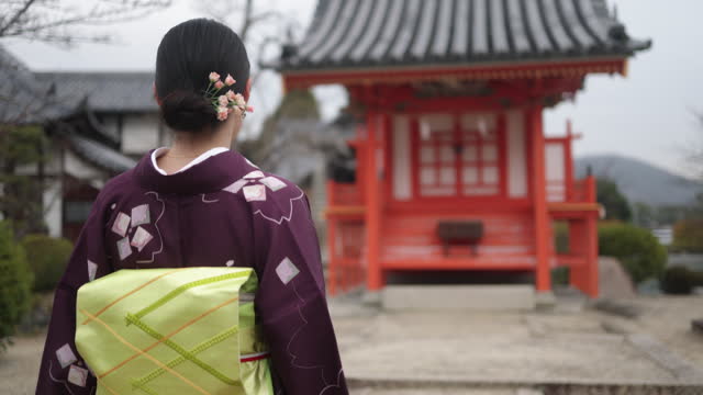 Rear view of Japanese woman in kimono walking in shrine- part 1 of 2