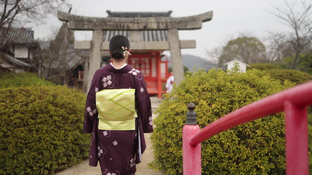 Rear view of Japanese woman in kimono walking across the shrine bridge - part 2 of 2