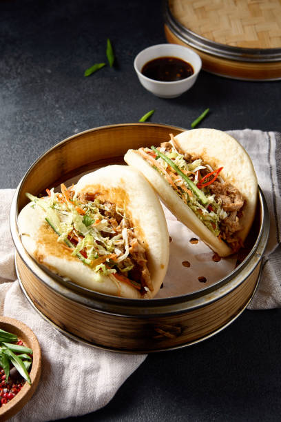 istock Savory Bao buns stuffed with pulled pork and fresh vegetables, captured from above on a dark background 2122346209