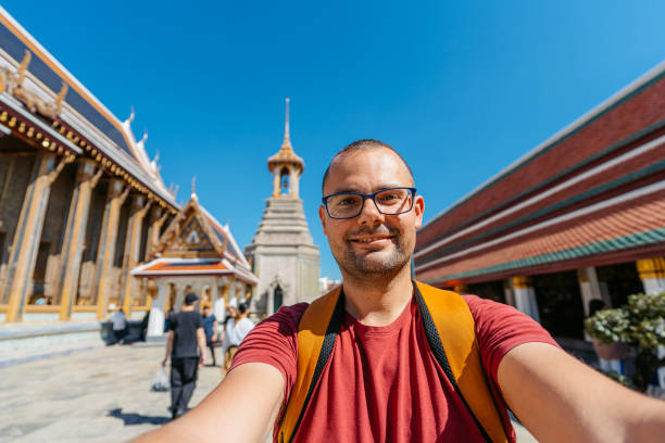 istock Young Man Taking Selfies At Wat Phra Kaew Complex (The Temple Of The Emerald Buddha) In Bangkok In Thailand 2122352546