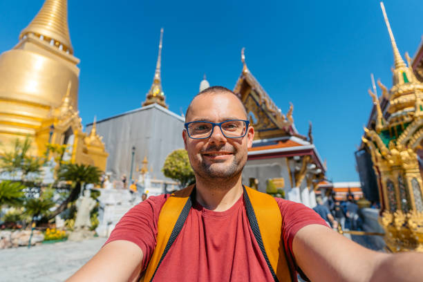 istock Young Man Taking Selfies At Wat Phra Kaew Complex (The Temple Of The Emerald Buddha) In Bangkok In Thailand 2122352613
