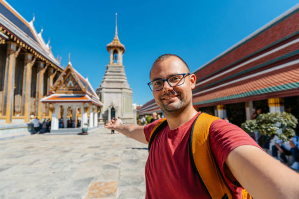 istock Young Man Taking Selfies At Wat Phra Kaew Complex (The Temple Of The Emerald Buddha) In Bangkok In Thailand 2122354211