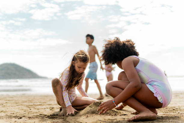 Child girls playing with sand on the beach