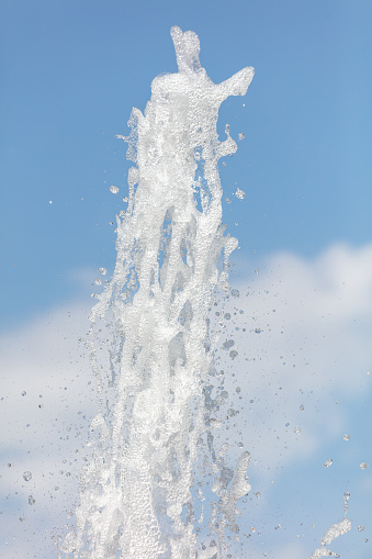Fountain splashes against the blue sky. Background.