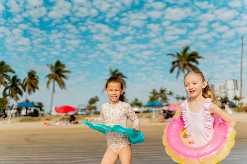 Children sisters with inflatable swim ring running to the sea on the beach