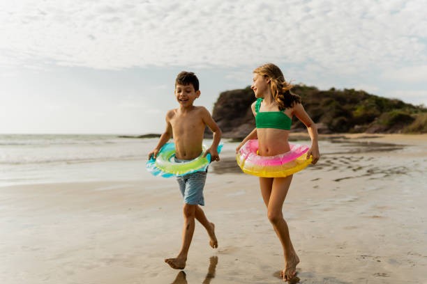 istock Friends children using inflatable swim ring and running through the beach 2122364658