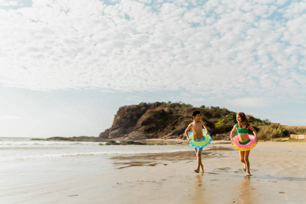 istock Friends children using inflatable swim ring and running through the beach 2122364666