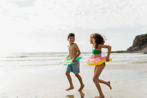 istock Friends children using inflatable swim ring and running through the beach 2122365173