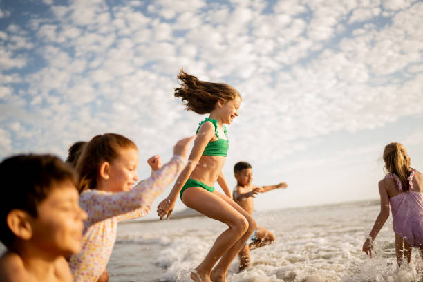 istock Friend children playing jumping in the waves on beach 2122371155