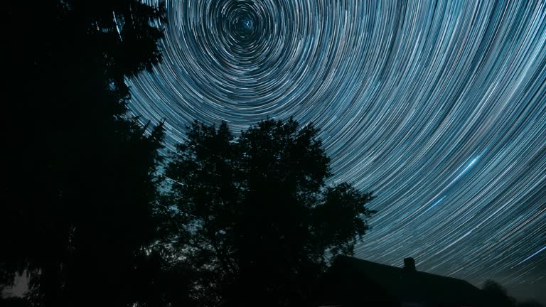 4k Timelapse Dramatic Twilight Sky With Amazing Stars Effects In Sky. Stars And Meteoric Track Trails Rotate Above Rural Old House Countryside Landscape. Time Lapse, Time-lapse. Spin Trails Of Stars