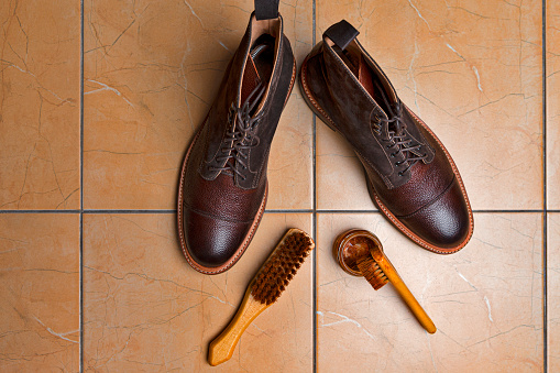Shoes Cleaning Accessories for Dark Brown Grain Brogue Derby Boots Made of Calf Leather Over Tile Background with Special Tools. Horizontal Orientation