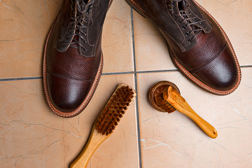 Shoes Cleaning Accessories for Dark Brown Grain Brogue Derby Boots Made of Calf Leather Over Tile Background with Special Tools. Horizontal Composition