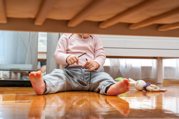 istock Baby with pacifier in mouth playing with sunglasses view from under crib 2122471419