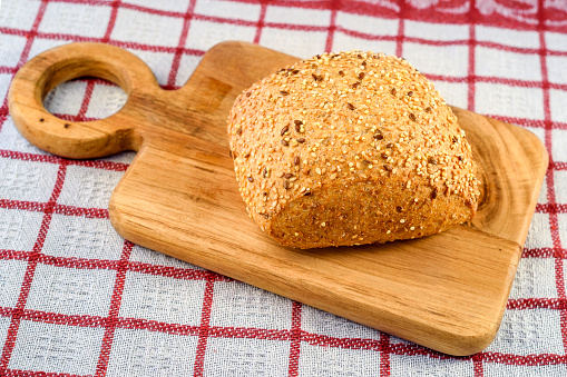 Rustic bread with sesame and flax seeds on the wooden cutter.