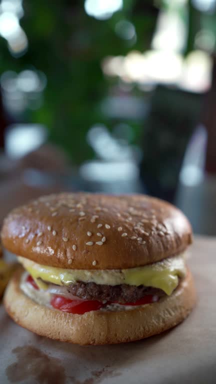 First person view of a waiter serving a delicious burger to a client at a table in a fast food restaurant