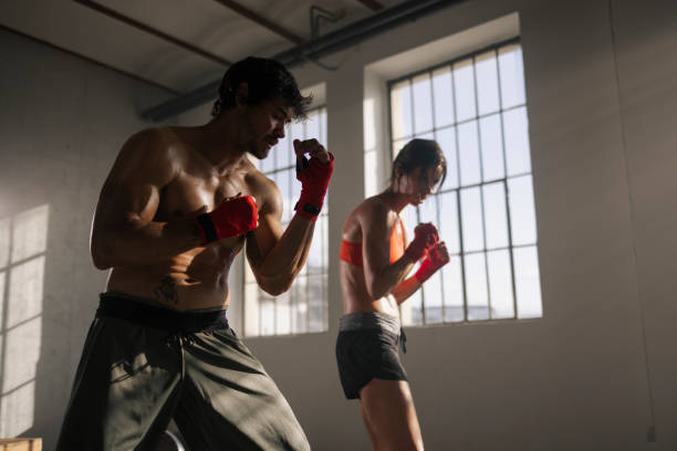 istock Two athletic individuals with boxing wraps prepare for sparring in a well-lit training gym, exuding focus and strength. 2122499324