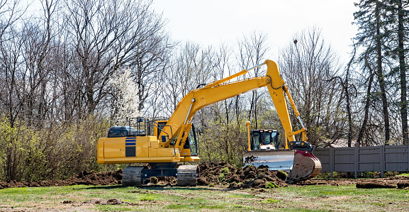 Backhoe clearing land for new construction development.