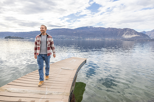 Man contemplates nature from above a wooden pier on a calm lake