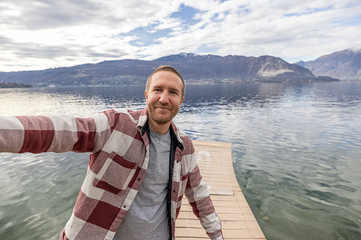 Man taking a selfie by the lake on a sunny bright afternoon