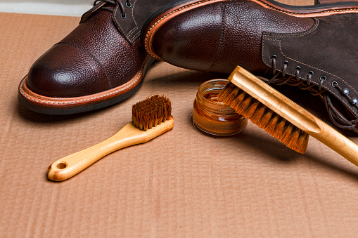 Various Shoes Cleaning Accessories for Dark Brown Grain Brogue Derby Boots Made of Calf Leather Over Tile Background with Special Tools. Horizontal Orientation Image