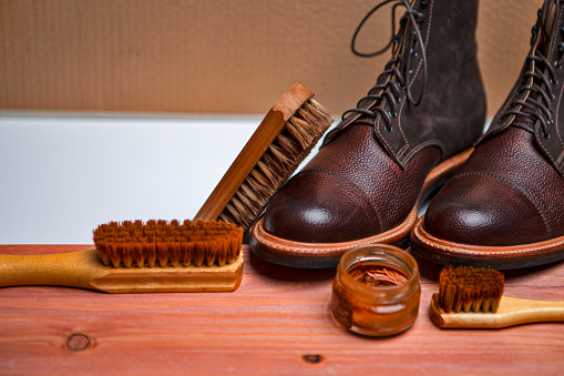 Shoes Cleaning Accessories for Dark Brown Grain Brogue Derby Boots Made of Calf Leather Over Paper Background with Cleaning Tools. Horizontal Image