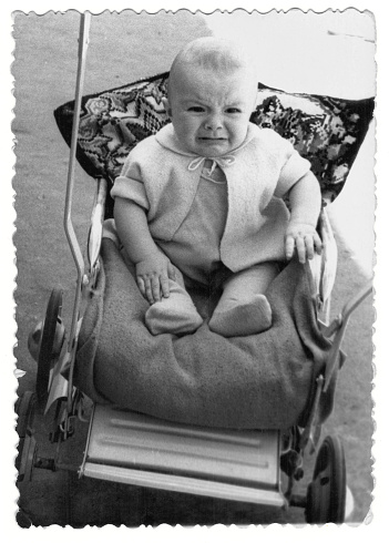 Vintage photo of a boy in a stroller. The baby is crying. Photo from 1961.