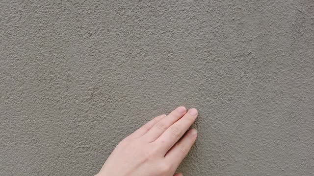 Rough concrete walls touched by hand