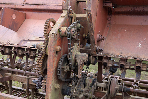 An old, rusted and disassembled seed drill for grain.