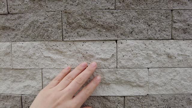 A rough artistic brick and stone wall touched by hand