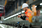 Portrait of a young male technician using a walkie talkie working and standing in a skytrain repair station.