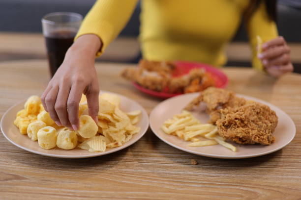 istock Woman eating fried chicken and snacks at home. 2122633517