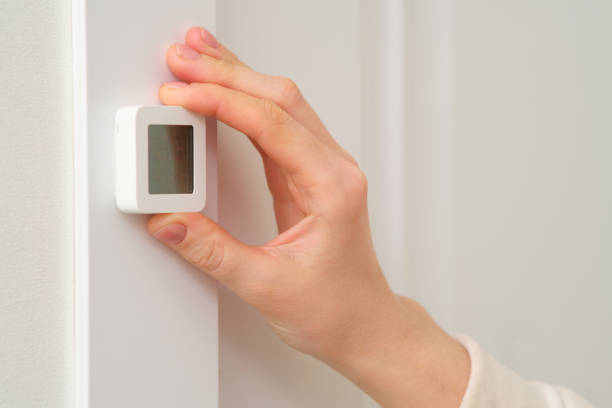 istock A woman's hand sets a thermometer on the wall, close-up 2122670515