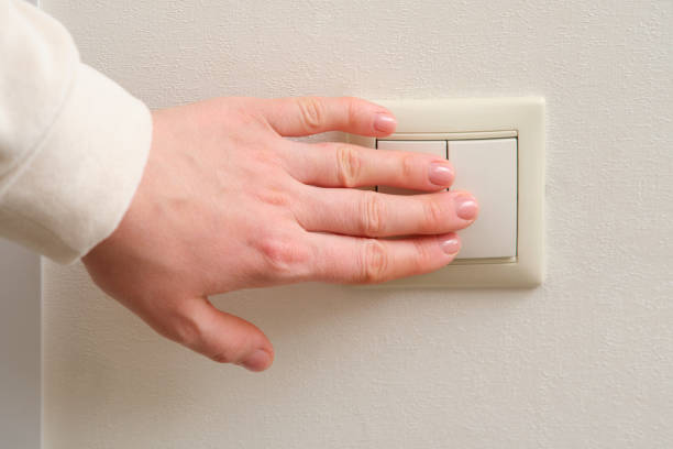istock A woman's hand turns on the light with an electric switch, close-up 2122670521
