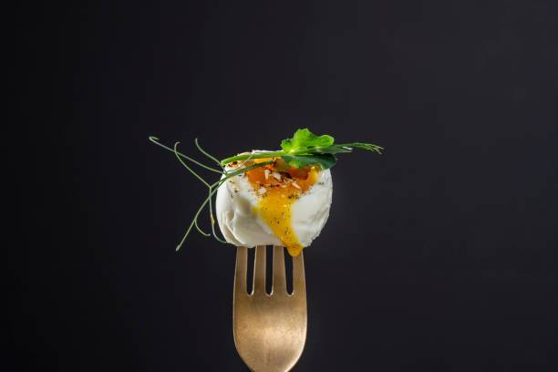 istock Soft-boiled egg with pea microgreens on a fork on a black background, breakfast time 2122690958
