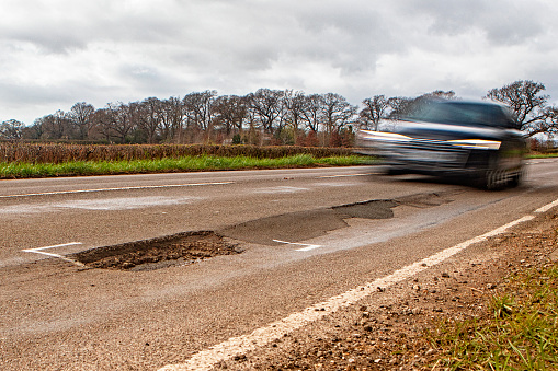 A pothole on a rural UK road in which the National Speed Limit  for single carriage roads applies (60mph).