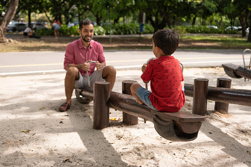 Father and son on seesaw in public park