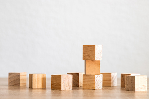 A stacked tower of wooden cubes among scattered blocks on a smooth table surface.