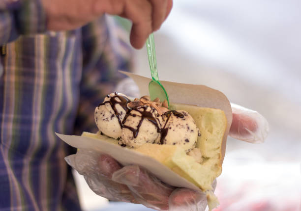 istock Male merchant's hands scooping vanilla chocolate chip ice cream into bread 2122776025