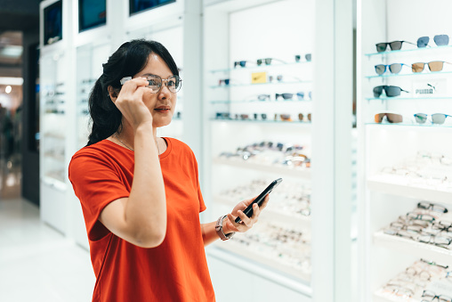 Woman selecting eyeglasses in optical store